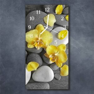 E-shop24, 60x30 cm, Hnn126326842 Nástěnné hodiny obrazové na skle - Orchidej žlutá na kamení